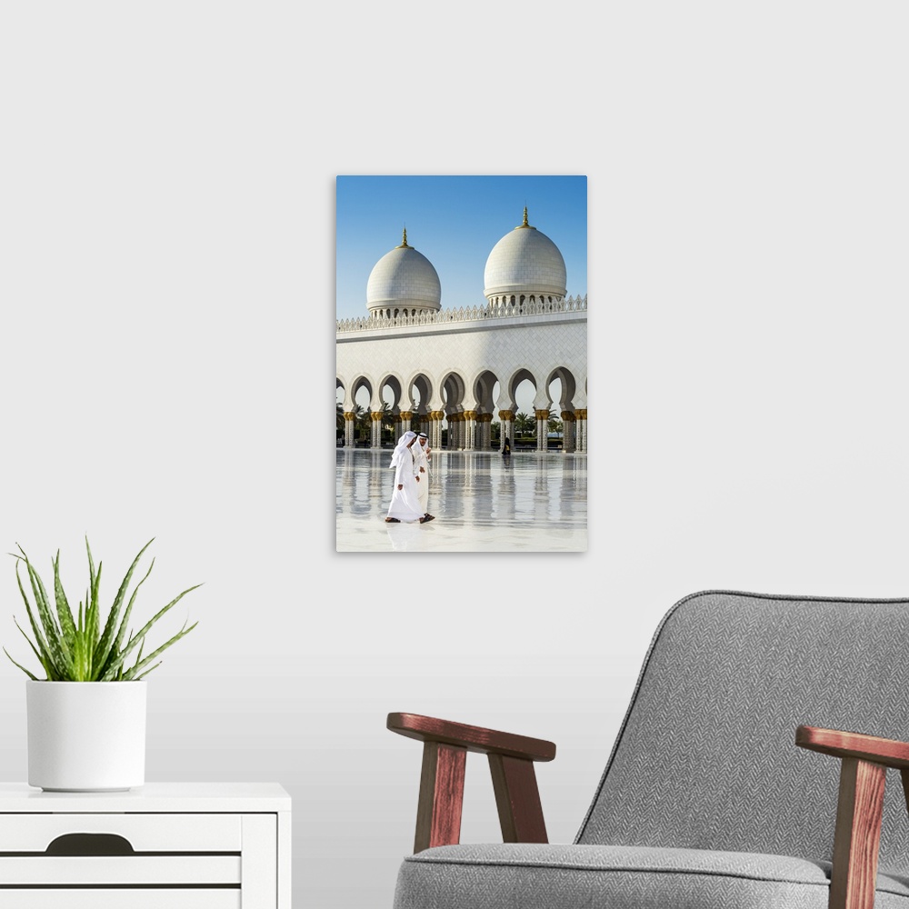 A modern room featuring Two Middle Eastern men traditionally dressed walking in the courtyard of the Sheikh Zayed Mosque,...
