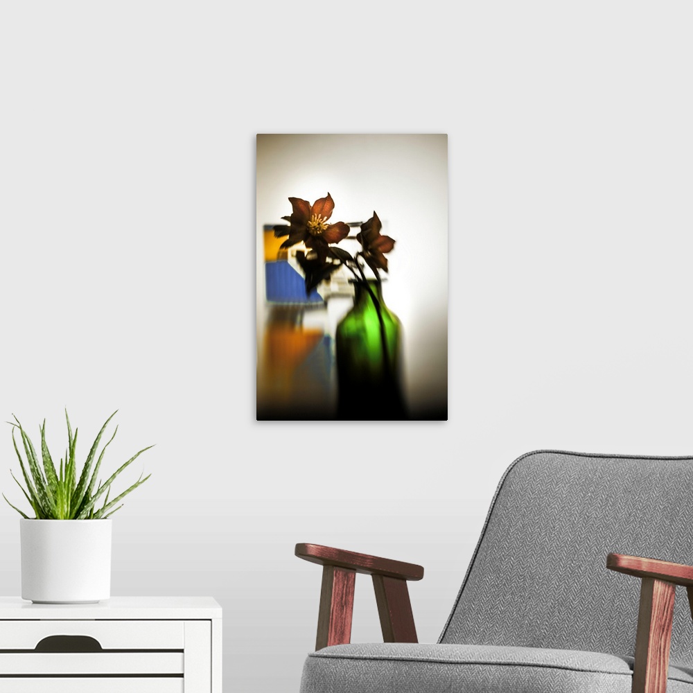 A modern room featuring Distorted photograph of Christmas roses in a green glass jar.