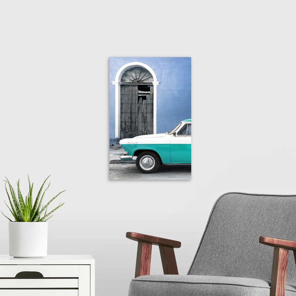 A modern room featuring Photograph of the front of a vintage turquoise and white car outside of a blue building with a br...