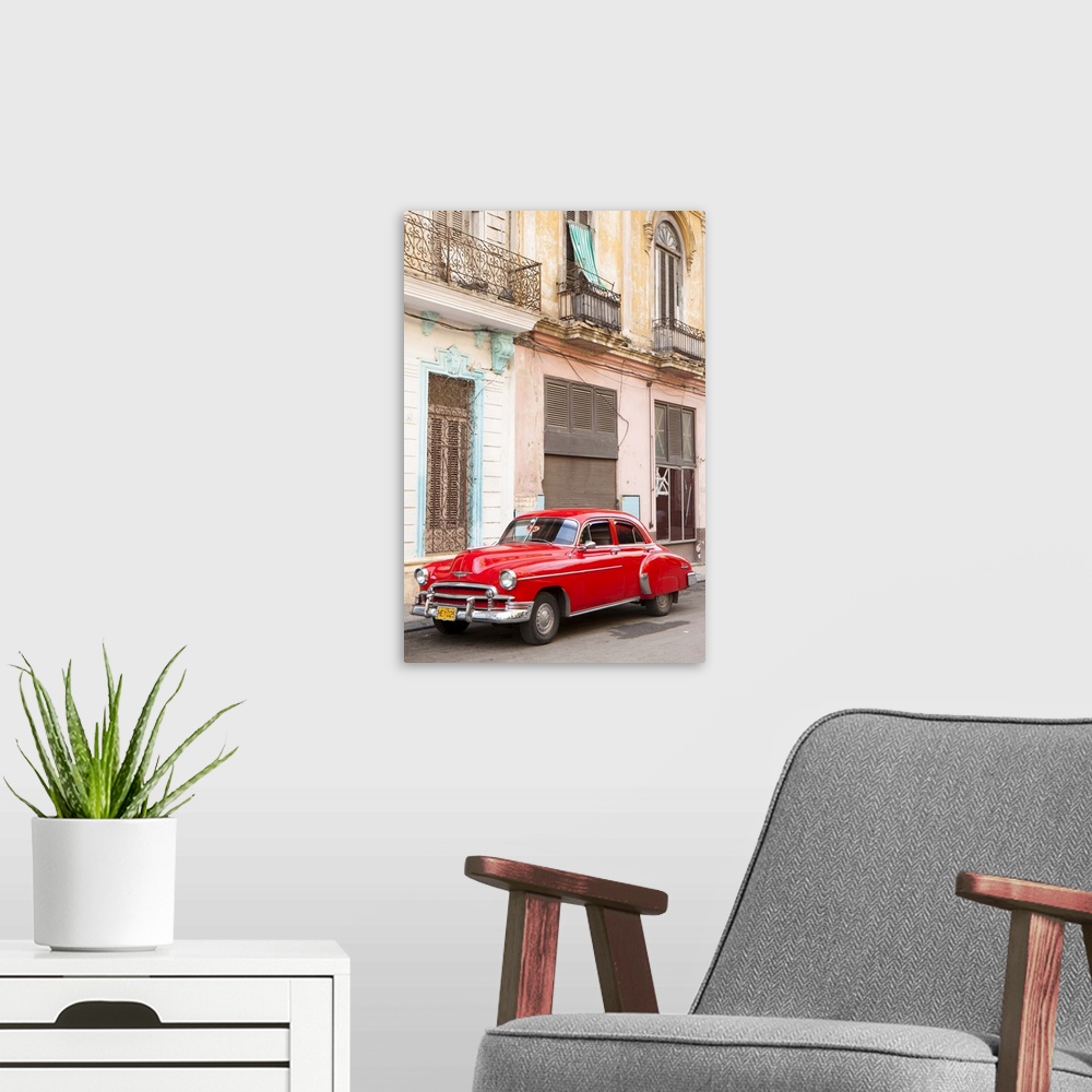 A modern room featuring Red American car parked outside faded Colonial buildings, Havana, Cuba