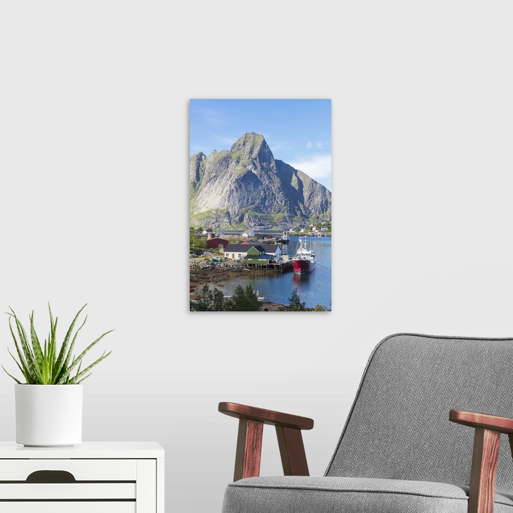 A modern room featuring Ship in the blue sea frames the fishing village and the rocky peaks, Reine, Moskenesoya, Lofoten ...