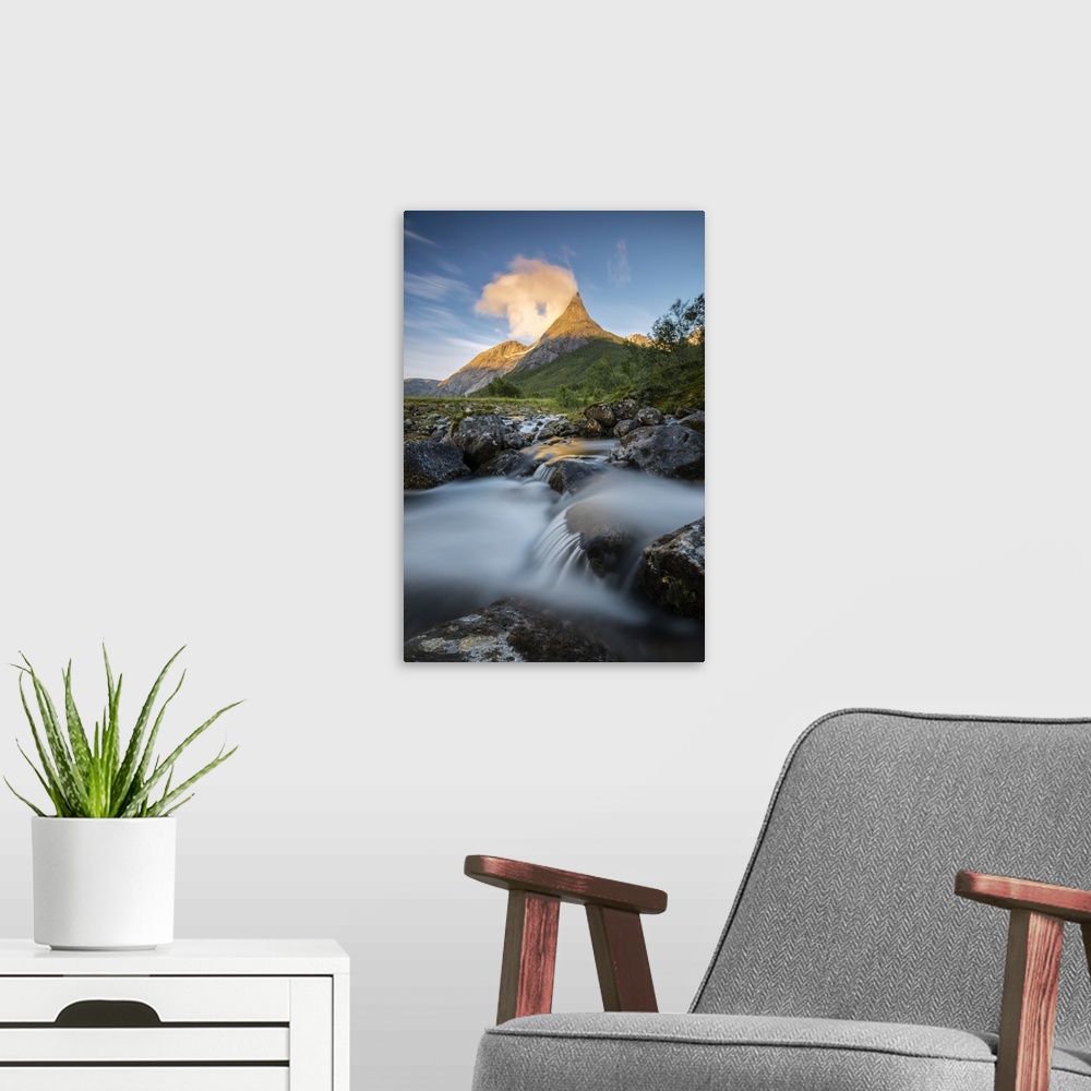 A modern room featuring Waterfall frames the Stetinden mountain peak illuminated by midnight sun, Tysfjord, Nordland, Nor...