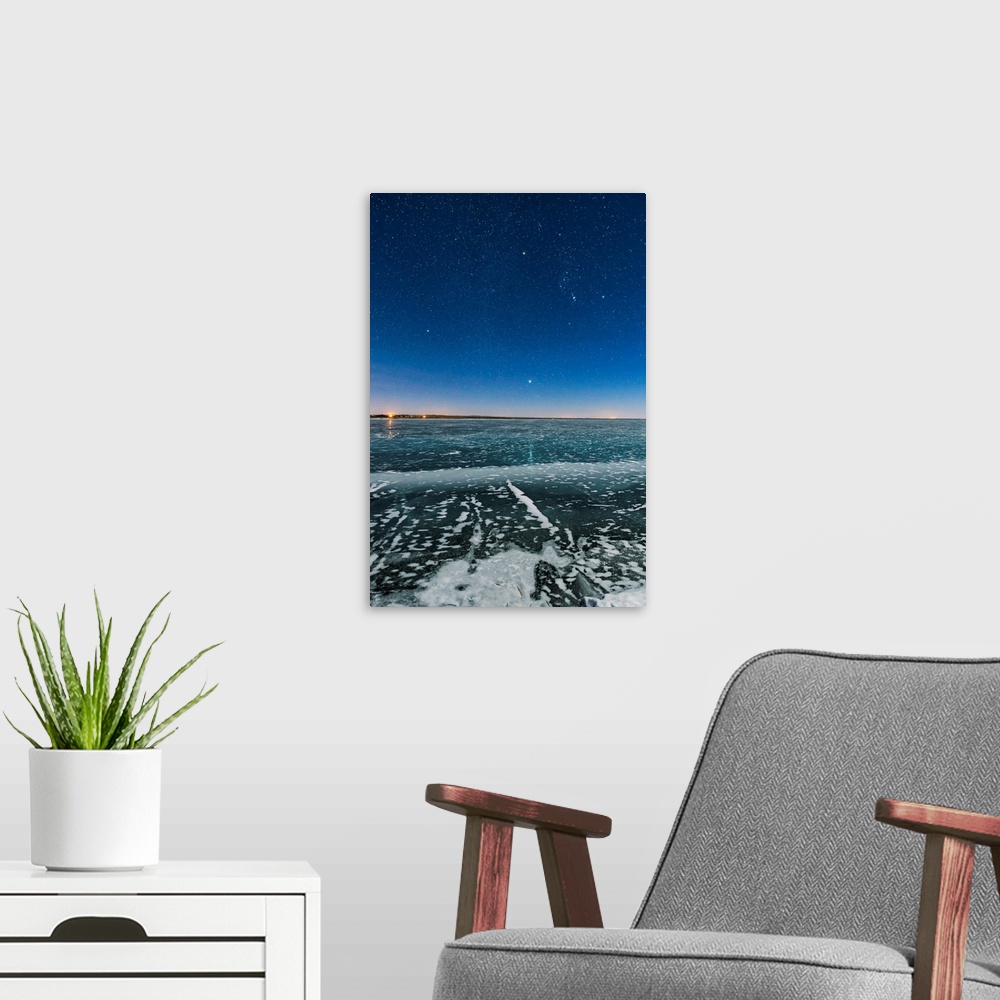 A modern room featuring Orion and the Dog Stars rising over a frozen Lake MacGregor in southern Alberta, Canada.