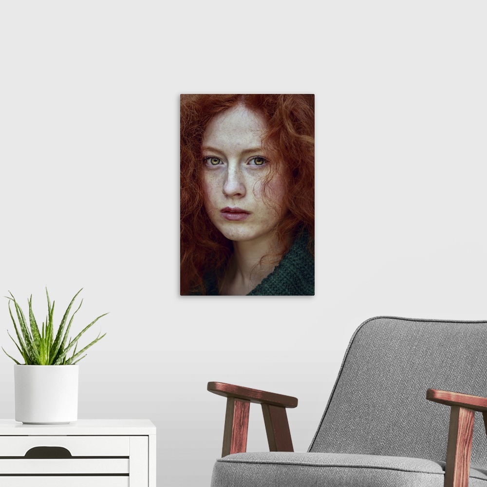 A modern room featuring Close-up portrait of female youth with red curly hair and piercing green eyes.