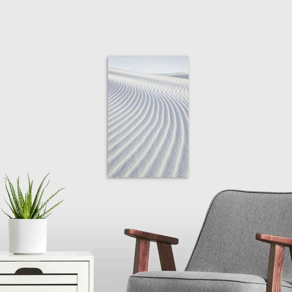 A modern room featuring A vertical photograph of ripples in the sand dunes created by the wind.