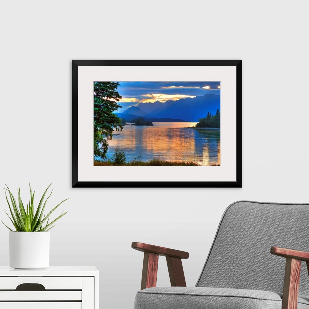 A modern room featuring A landscape photograph of morning light reflecting on a lake in the mountains surrounded by trees.