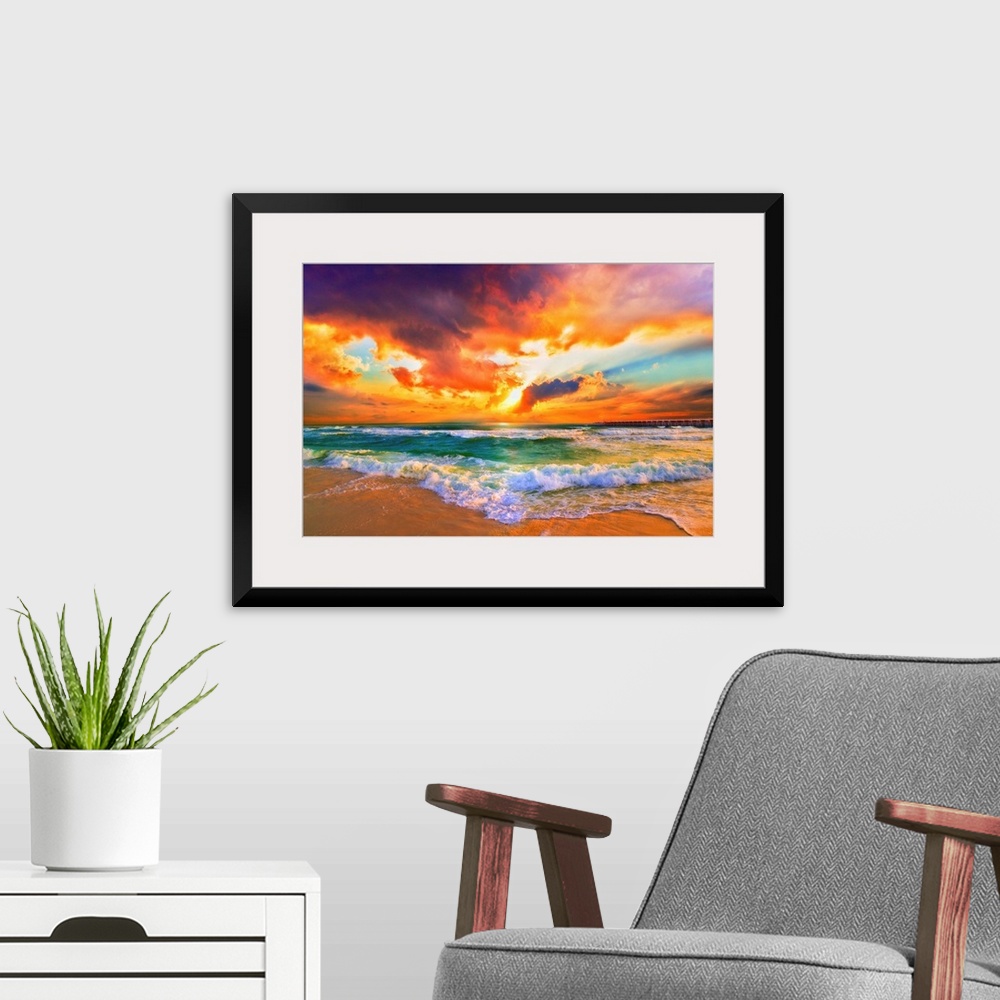 A modern room featuring A red, orange and purple sunset on the beach. Beautiful ocean waves roll onto the sea shore.