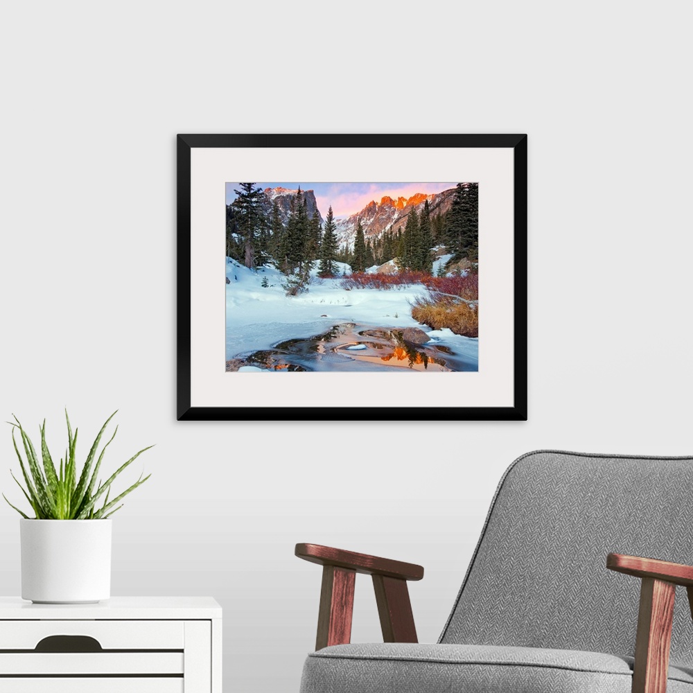 A modern room featuring Photograph of a little creek by snow-covered ground and trees with the Rocky Mountains in the bac...