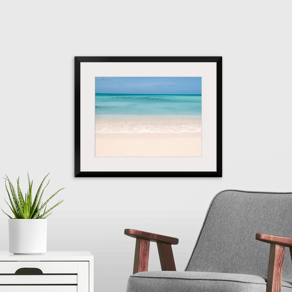 A modern room featuring Horiztonal wall art of a serene beach and a still sea on a clear day in Aruba.