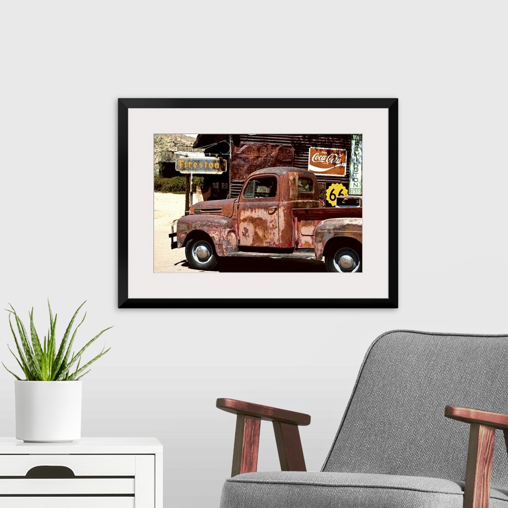 A modern room featuring A very rusty pickup truck sits by a weathered gas station on Route 66.