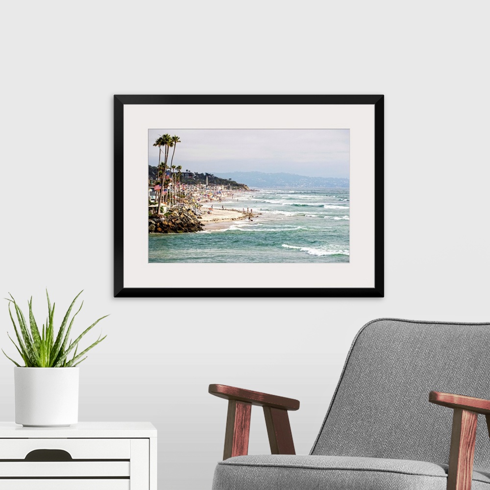 A modern room featuring Landscape photograph of the La Jolla coast filled with beach goers and palm trees.