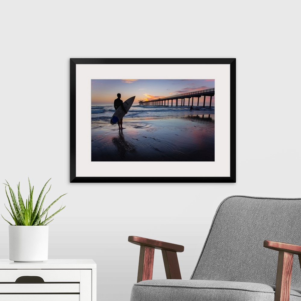 A modern room featuring Silhouetted photograph of a man holding a surf board on the shore of Ocean Beach in San Diego, Ca...
