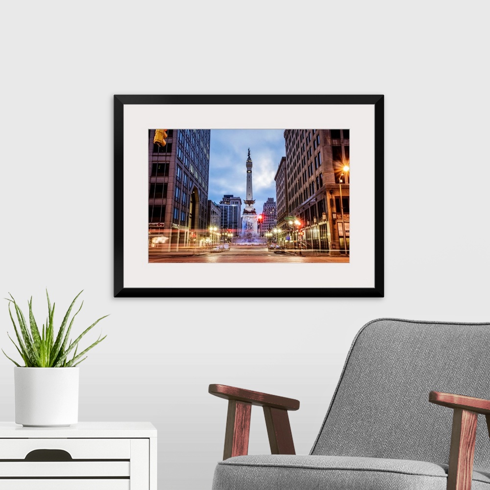 A modern room featuring The Soldiers and Sailors Monument in the evening with lights from passing traffic in Indianapolis...