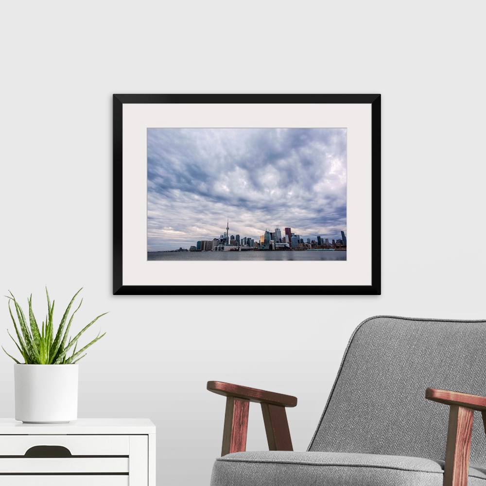 A modern room featuring Toronto city skyline under dramatic clouds, Ontario, Canada.