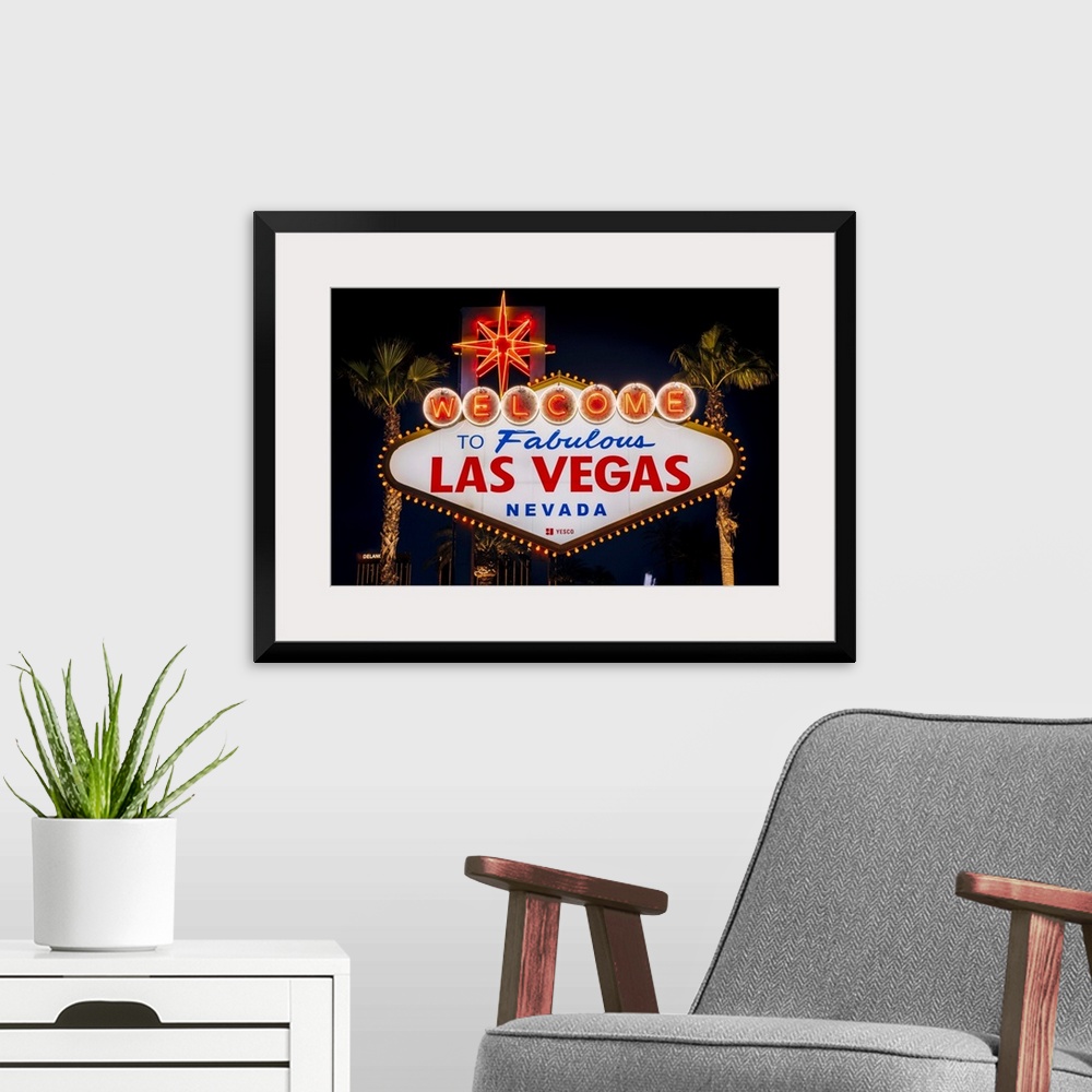 A modern room featuring The famous "Welcome to Las Vegas, Nevada" sign is lit at night.