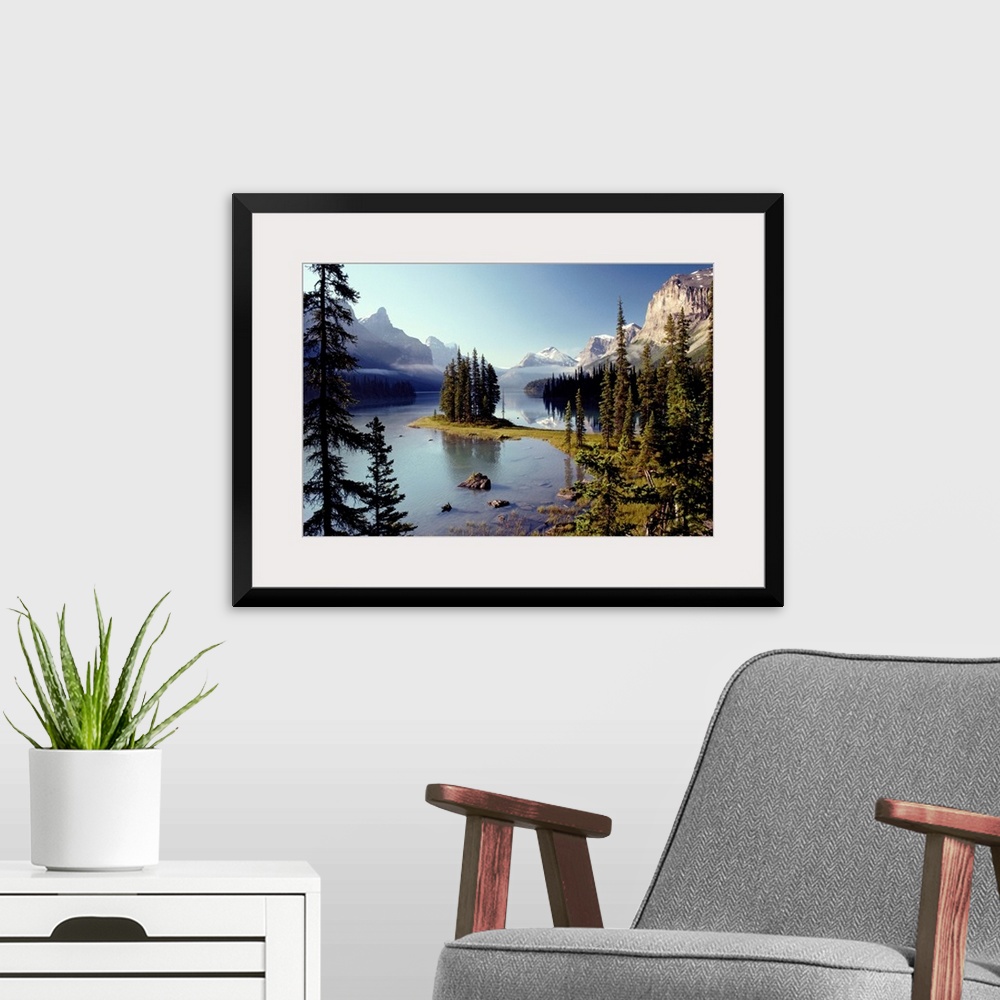 A modern room featuring Large wall print of a forest of evergreens meeting and jutting out into a clear lake surrounded b...