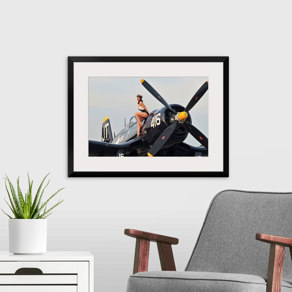 A modern room featuring 1940's style Navy pin-up girl sitting on a vintage World War II Corsair fighter plane.