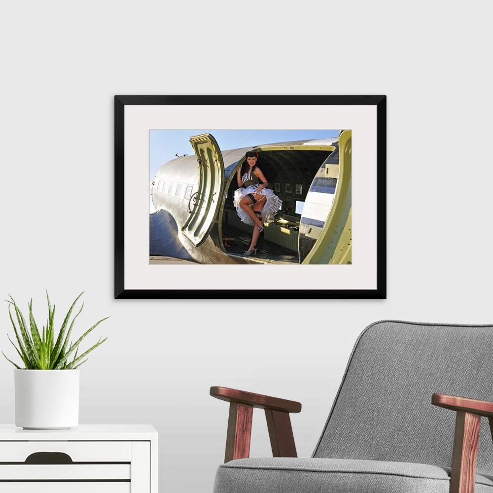 A modern room featuring Sexy 1940's style pin-up girl with stockings, standing inside of a World War II C-47 Skytrain air...