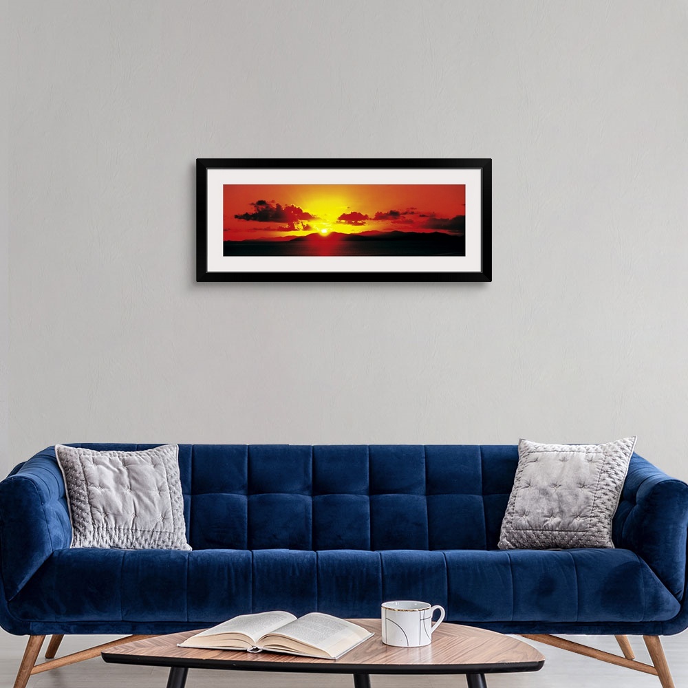 A modern room featuring Panoramic photograph of a fiery sunset over a mountain landscape on the horizon, in the British V...
