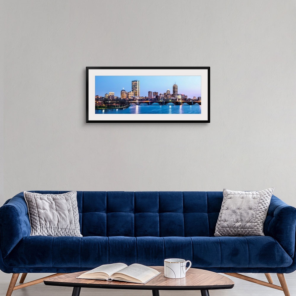 A modern room featuring Panoramic view of the Boston City skyline illuminated at night, with the Longfellow Bridge in the...