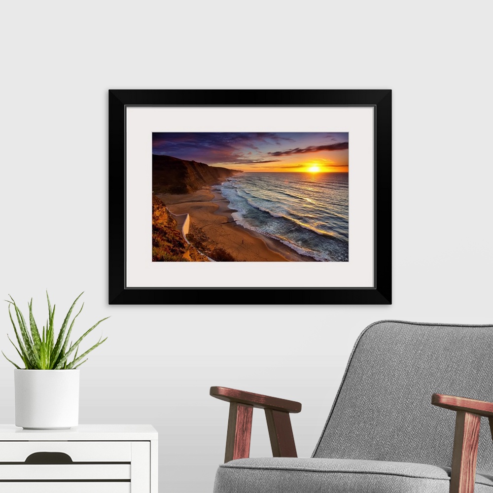 A modern room featuring Warm landscape photograph of the sunset in Praia Do Magoito, Portugal.