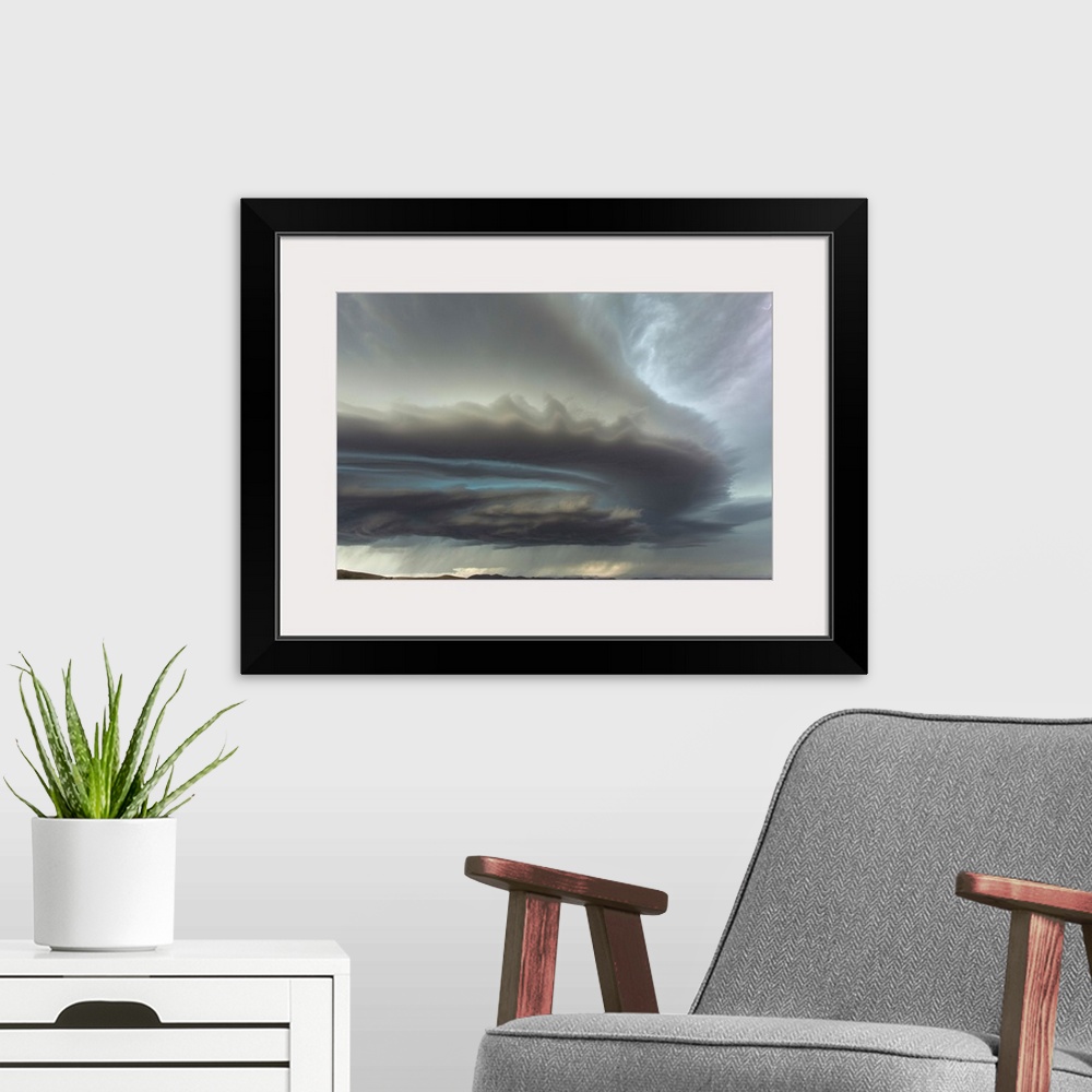 A modern room featuring Large menacing storm clouds rolling over a countryside landscape.