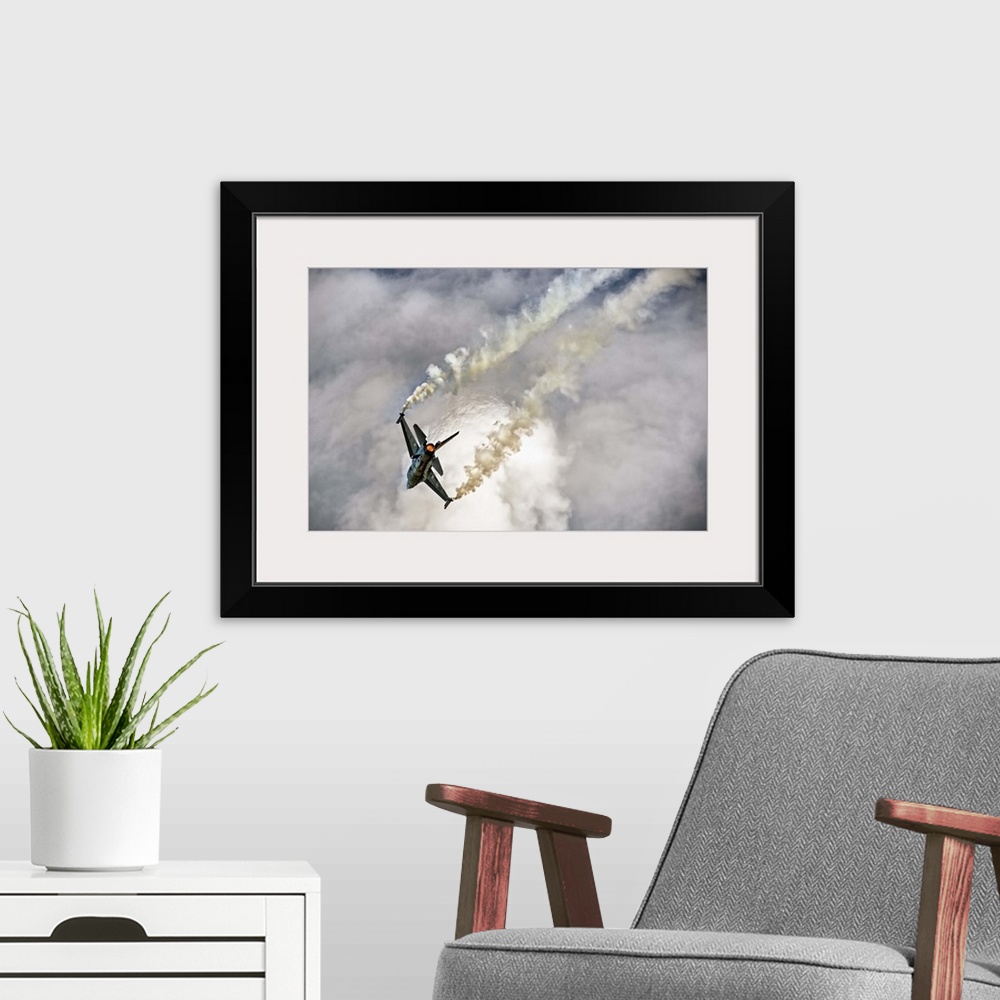 A modern room featuring A jet airplane dives in the sky, leaving twin contrails from its wings.