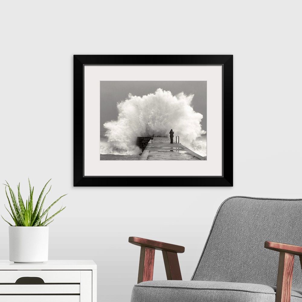 A modern room featuring A photographer standing on a pier with waves crashing.