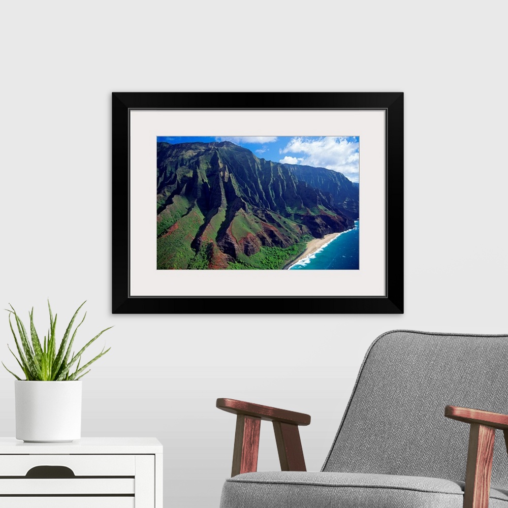 A modern room featuring This large piece is an aerial photograph of huge mountains on the coast of a Hawaiian island.