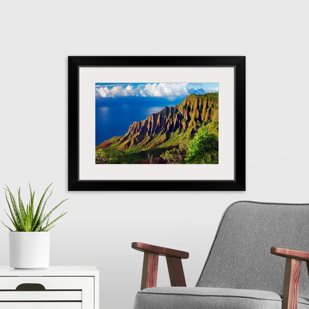 A modern room featuring This is a landscape photograph of mountain cliffs on a view down a hillside to the ocean and cumu...
