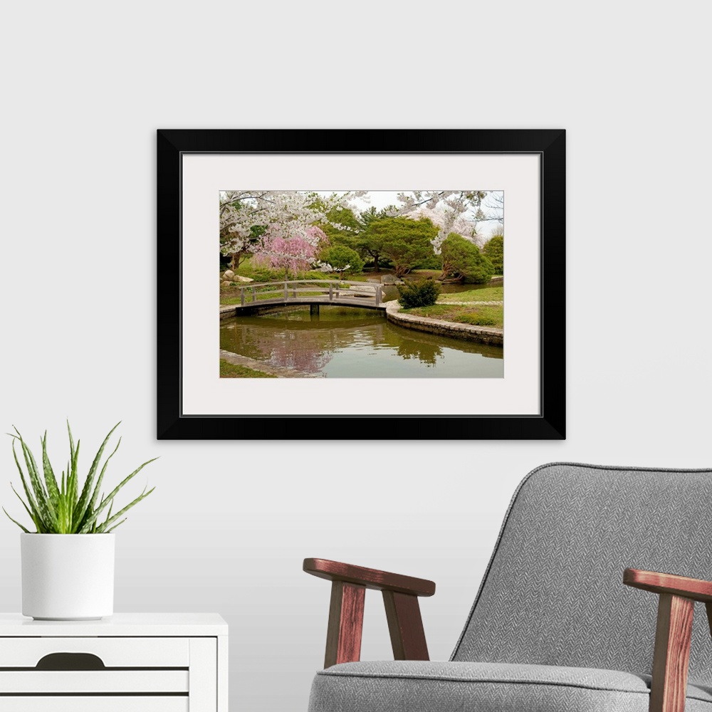 A modern room featuring Large canvas photo art of a bridge crossing a river with flowering Japanese trees sprinkled aroun...
