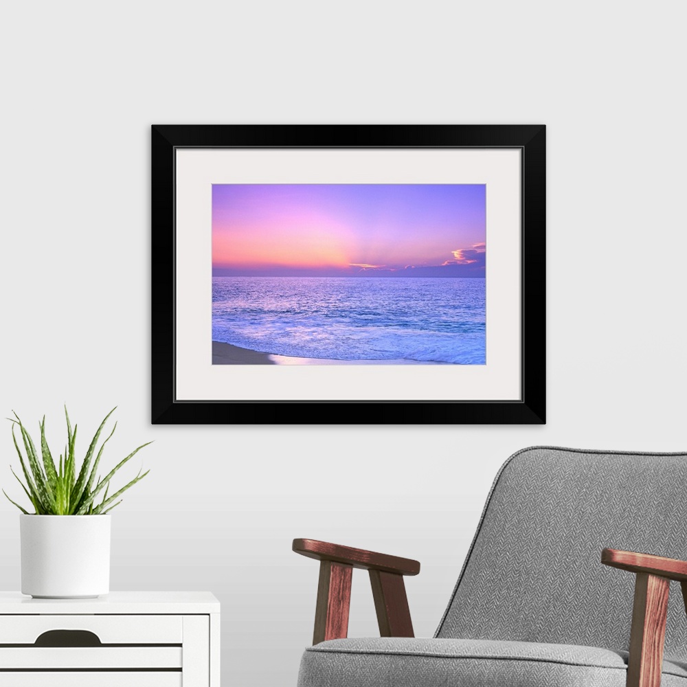 A modern room featuring A breathtaking photograph of a sunset over the vast ocean giving the overall picture a soft color...