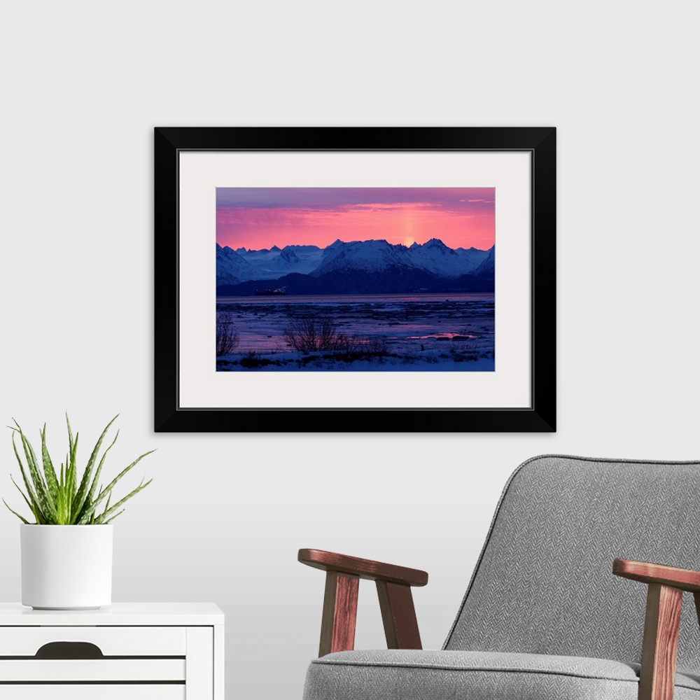 A modern room featuring Photo print of rocky mountains with the sun setting behind them.