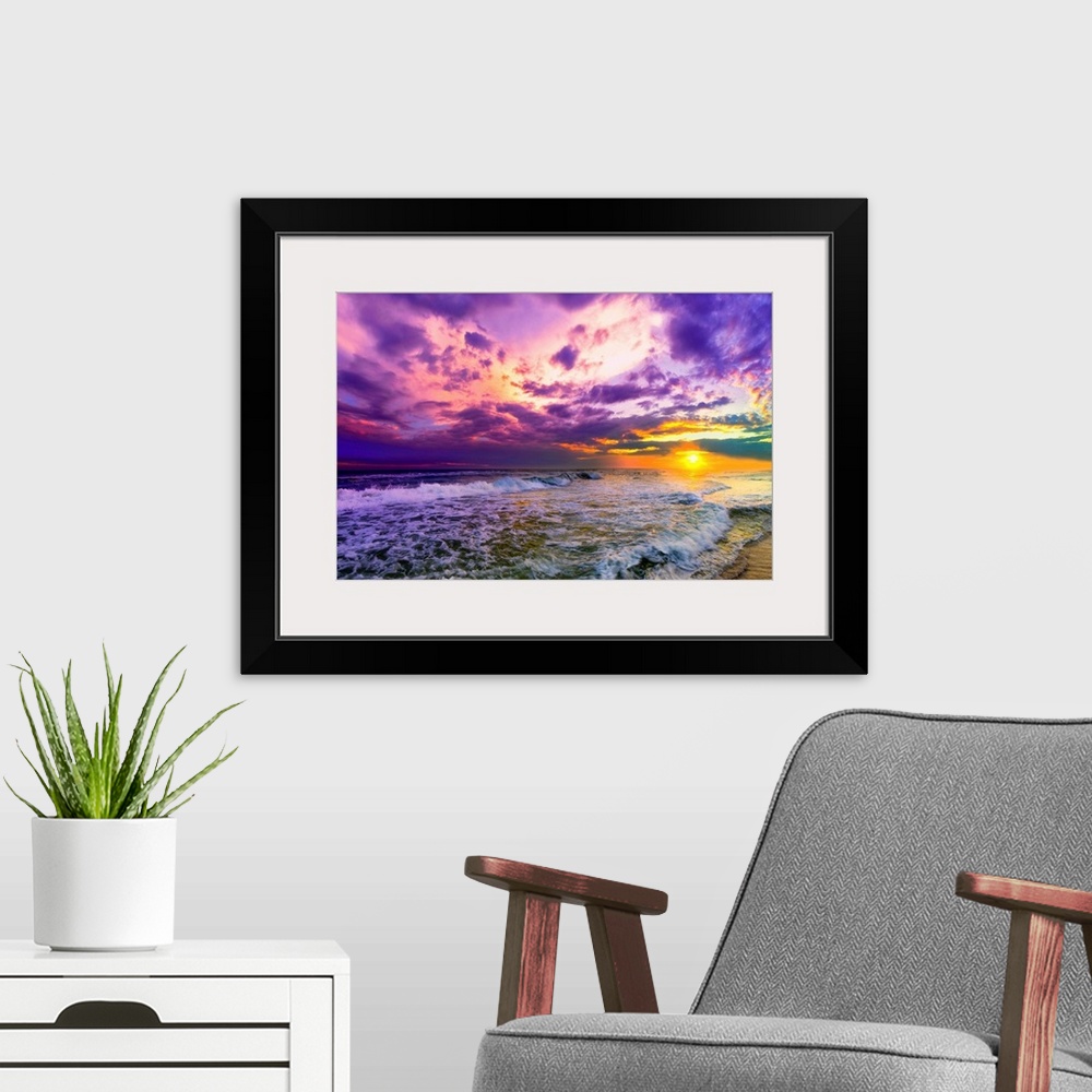 A modern room featuring A beach sunset with beautiful pink and purple clouds. The ocean is littered with foamy waves unde...