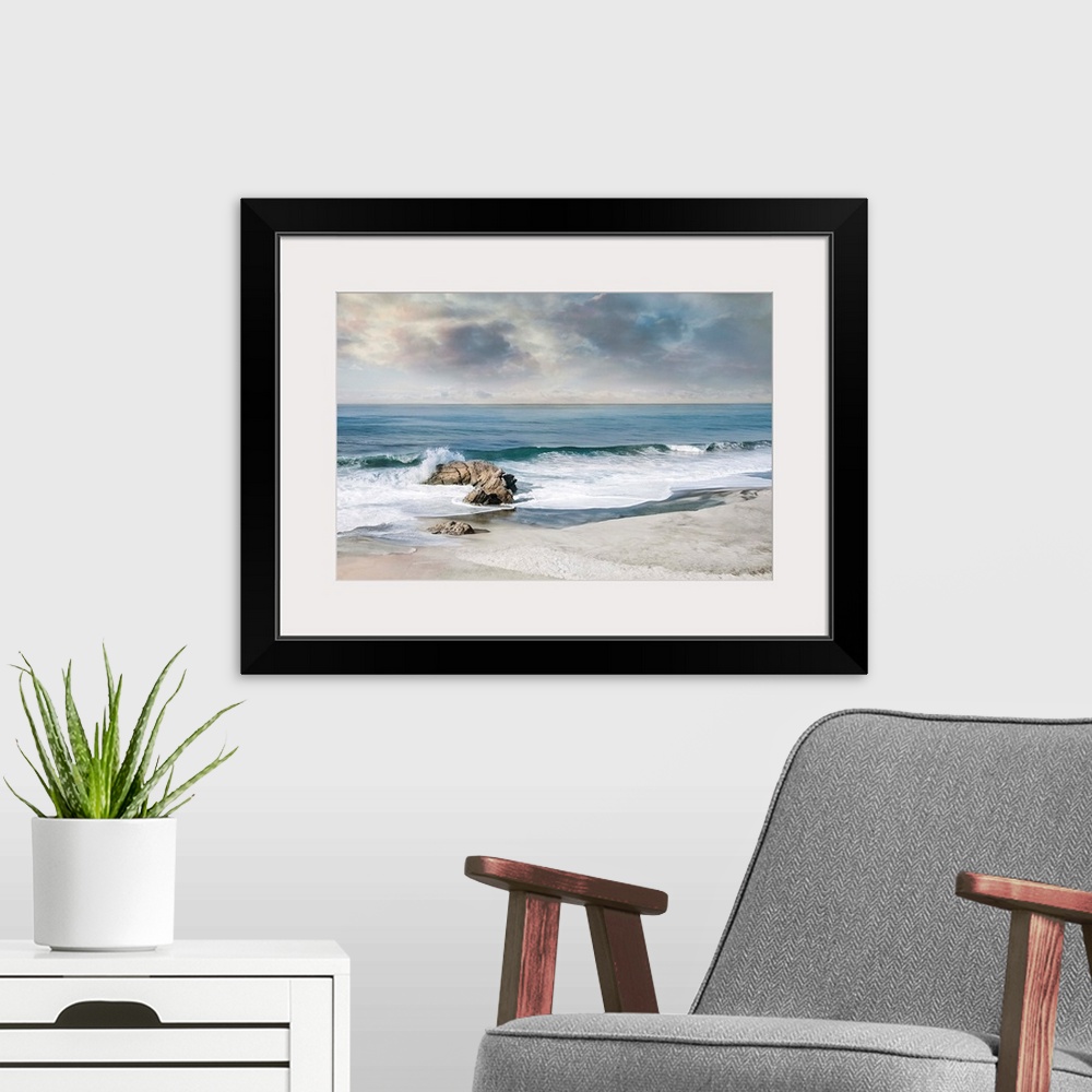 A modern room featuring Landscape photograph of waves crashing onto a rock on the sandy shore.