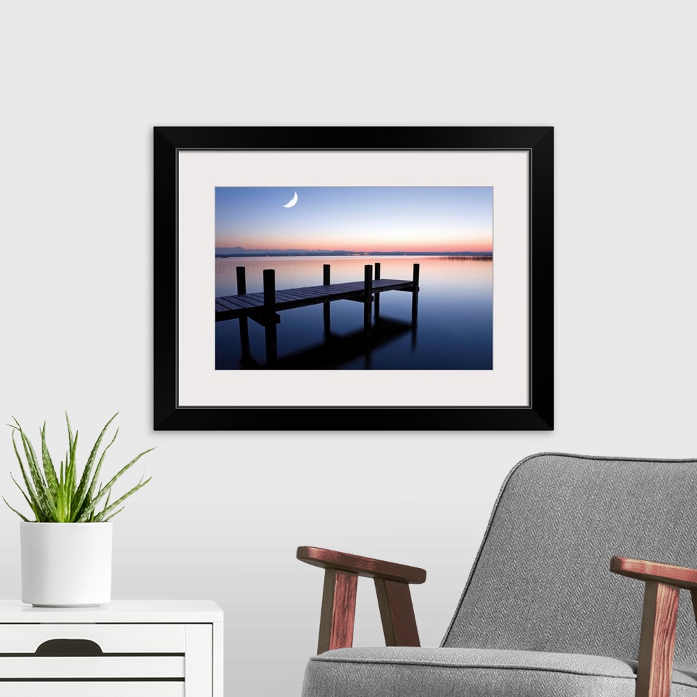 A modern room featuring Sunset photograph of a dock over calm water and a half moon in the sky.