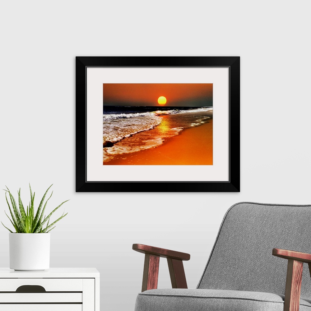 A modern room featuring This canvas wall art is a photograph of the sun dropping below the horizon in this landscape at t...
