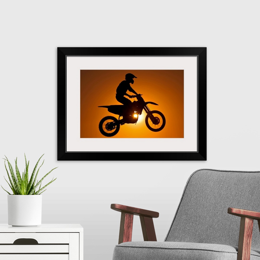 A modern room featuring Silhouette of motocross race in mid air at sunset.