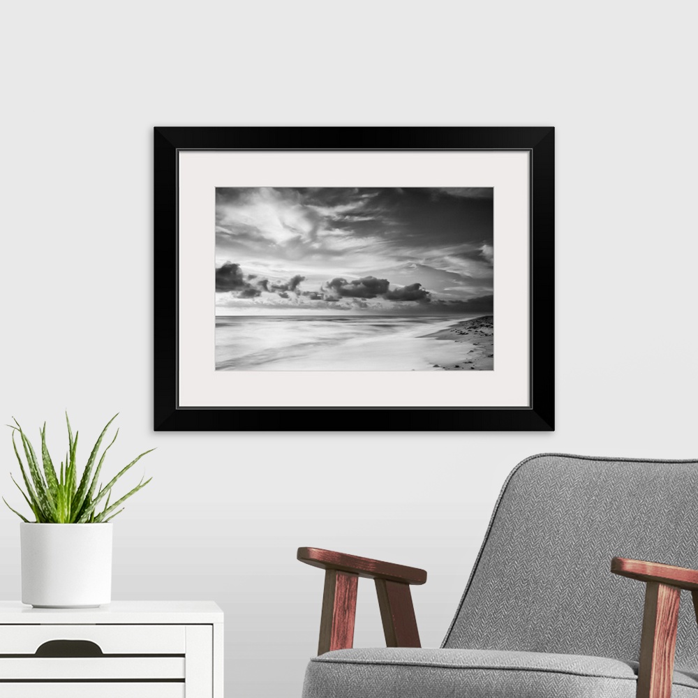 A modern room featuring A black and white photograph of a sunrise sky with clouds obscuring the view.
