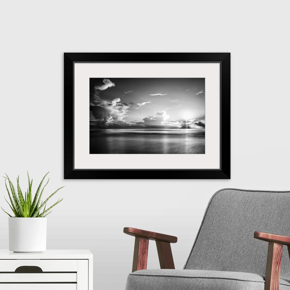 A modern room featuring A black and white photograph of a sunrise sky with clouds obscuring the view.