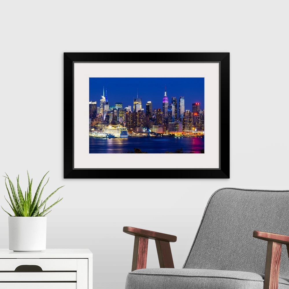 A modern room featuring Canvas print of the NYC cityscape lit up in colored lights along a waterfront.