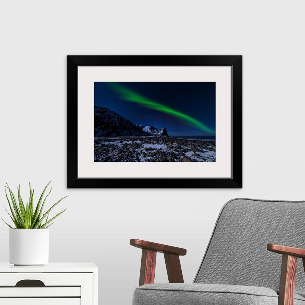 A modern room featuring A photograph of the northern lights over a snowy rugged landscape with mountains in the distance.