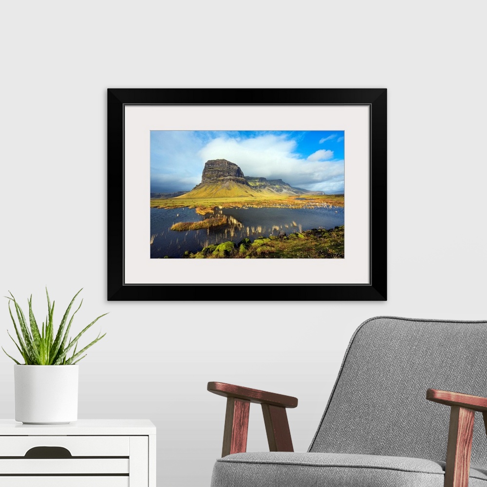 A modern room featuring Fine art photograph of the Icelandic landscape with a tall mountain surrounded by clouds.