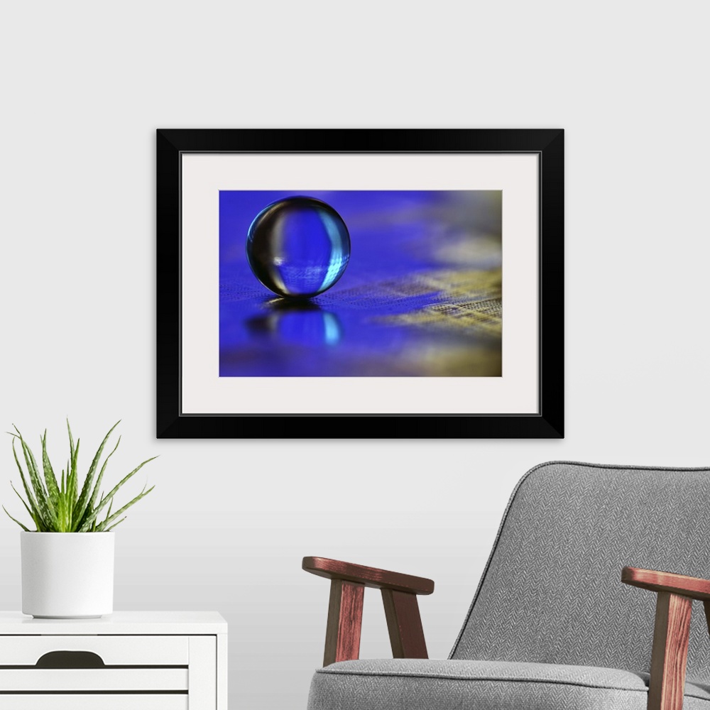 A modern room featuring A macro photograph of a water droplet sitting o a blue surface.