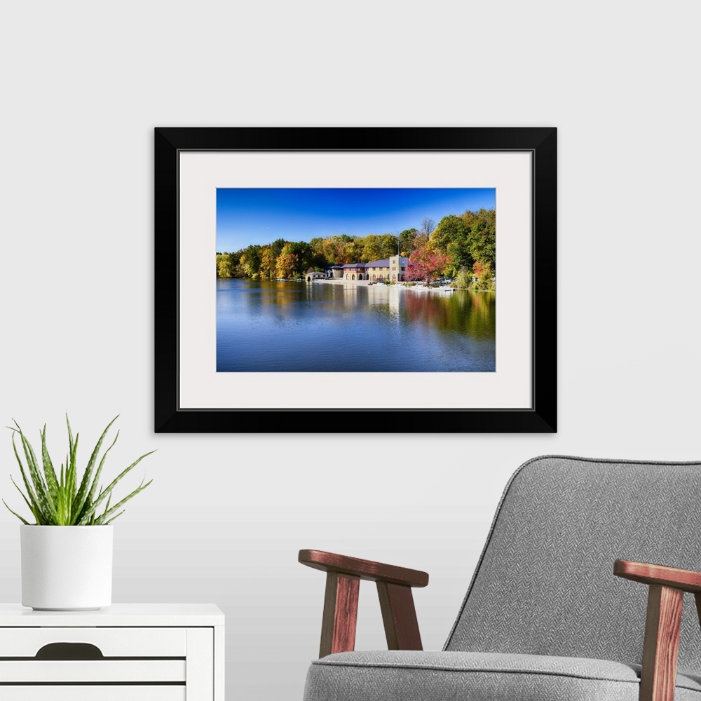 A modern room featuring Buildings at the edge of the calm waters of Lake Carnegie in New Jersey in the fall.