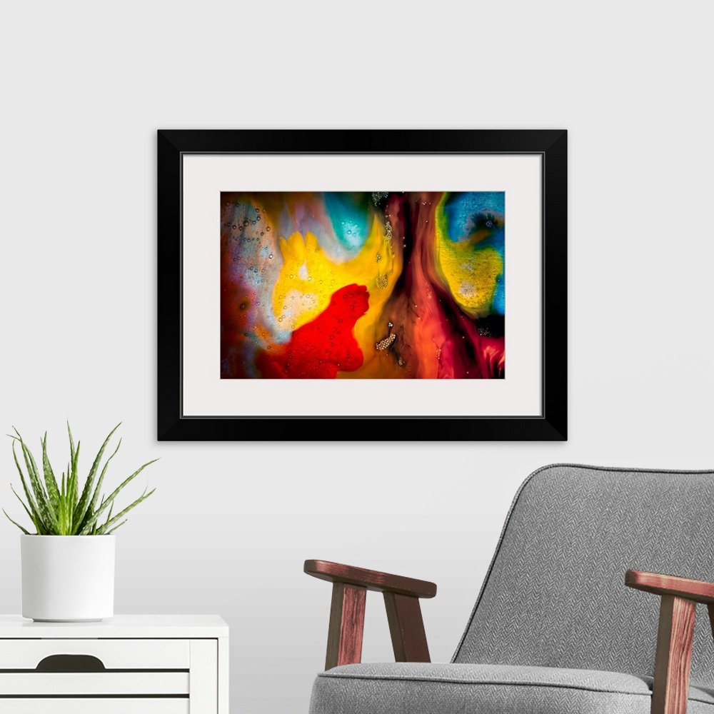 A modern room featuring Fine art abstract photograph of swirling paint in bright reds and yellows.