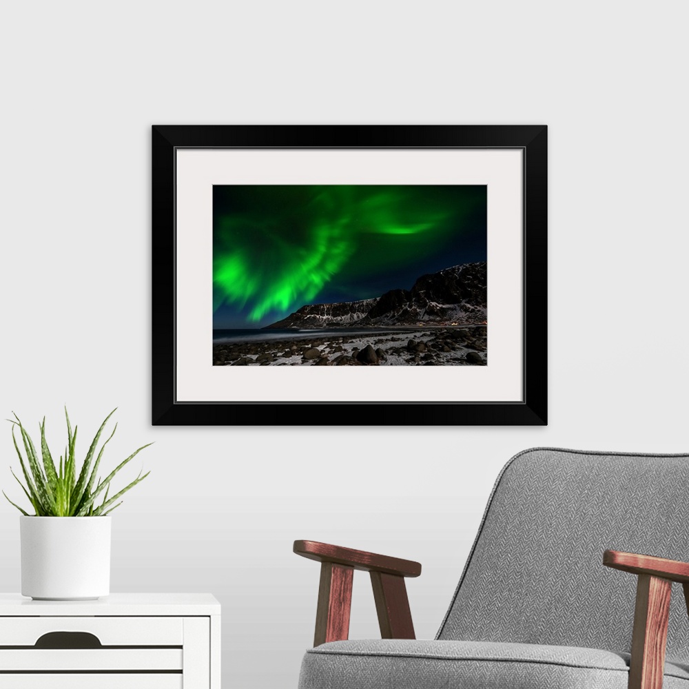 A modern room featuring A photograph of the northern lights seen above a rugged winter landscape.