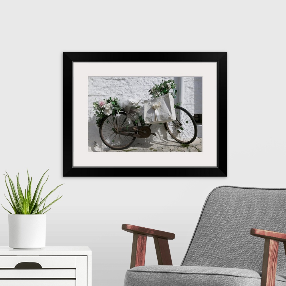 A modern room featuring A bike with rusty gears covered in beautiful roses with a decorative ribboned tote bag leaning ag...