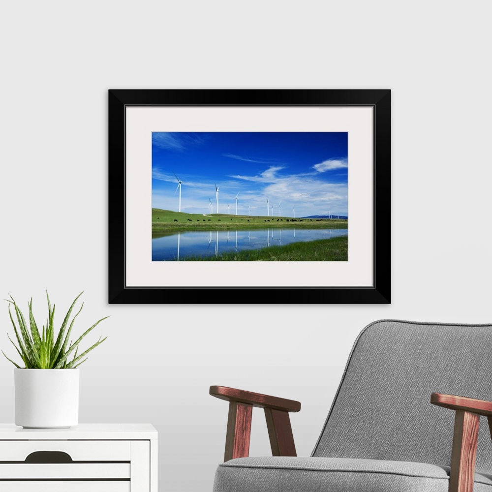A modern room featuring Herd of cattle grazing beneath row of wind farm turbines, reflection in pond water, Montana