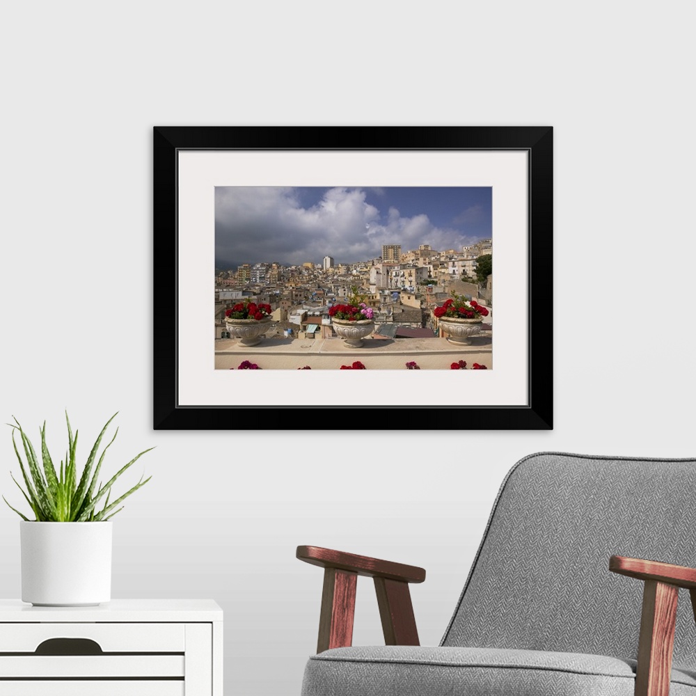 A modern room featuring Canvas photo print of three flowers planted in pots along a balcony with an Italian city in the d...